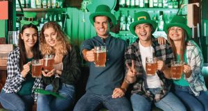 5 people wearing green hats and holding beers