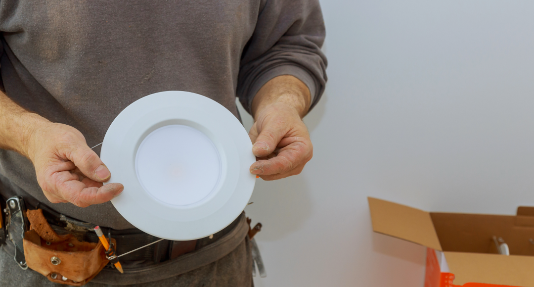 Man holding an LED downlight.